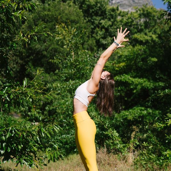 Woman in a calm yoga pose outdoors with green nature background.
